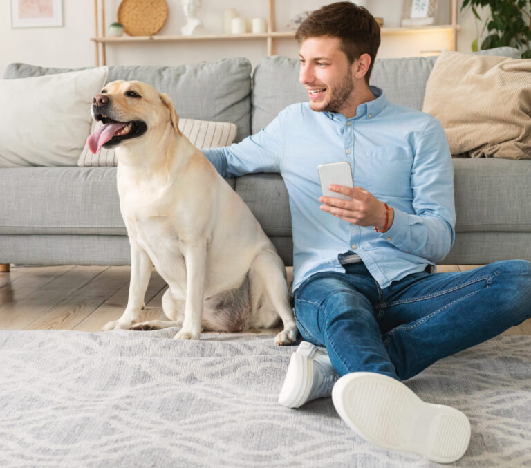 Portrait of young man with dog using mobile phone